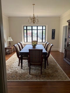 A long dining table set for guests beneath a chandelier in the Deanery's dining room